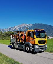 Lkw auf einer Straße vor Berglandschaft bei klarem Himmel.