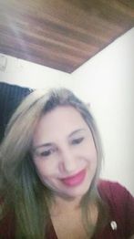 Mulher sorridente com cabelo loiro em ambiente interno, usando blusa vermelha.