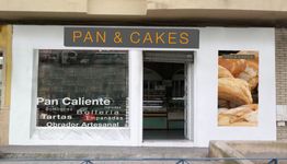 Fachada de una panadería llamada "Pan & Cakes" con cartel de panes y lista de productos ofrecidos.