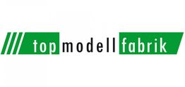 Grünes Logo mit Schriftzug "top modell fabrik" in Weiß und Schwarz auf grünem Hintergrund.