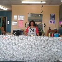 Person standing behind a counter with a white pattern in an office or store setting.