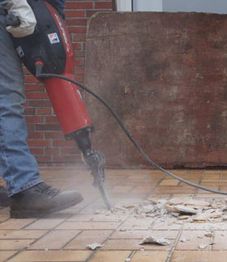 Worker using a jackhammer to break up old tiles.
