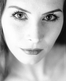 Nahaufnahme eines Gesichts einer Frau in Schwarzweiß, die direkt in die Kamera blickt.