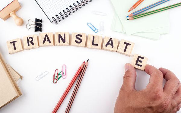 Holzwürfel mit dem Aufdruck "Translate" werden aufgereiht, um Übersetzungsdienste für KMUs zu verbildlichen.
