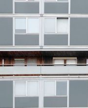 Wohnblock mit grauen Fassaden. Balkon mit Holzverkleidung und brasilianischer Flagge im Fenster.