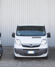 Tre furgoni Opel parcheggiati davanti a un edificio grigio.