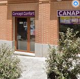 Fachada de tienda "Concept Confort" con puerta de vidrio y plantas al frente.