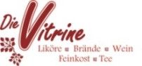 Logo mit Schriftzug "Die Vitrine" in Rot. Kategorien: Liköre, Brände, Wein, Feinkost, Tee.