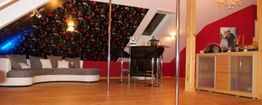 Gemütliches Wohnzimmer im Dachgeschoss mit Sofa, Bartresen, Tanzstange und modernem Dekor.