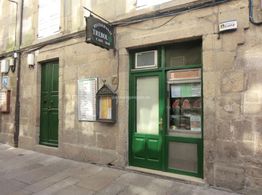 Fachada de un restaurante de piedra con puertas y ventanas verdes, en una calle tranquila.