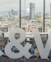 Oficina con letras "C&W" grandes y vista a la ciudad a través de ventanas.