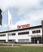 Prédio moderno da empresa Brose com três bandeiras hasteadas na frente.