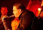 Ein Musiker spielt Saxophon auf einer Bühne mit rotem Licht.