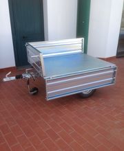 Carrello in metallo vuoto su pavimento in cotto, vicino a una porta verde.