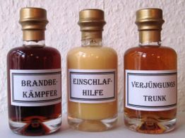 Drei Flaschen mit Etiketten: Brandbekämpfer, Einschlafhilfe, Verjüngungstrunk.
