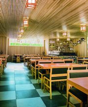 Restaurante vacío de estilo moderno con mesas de madera y techo de listones.