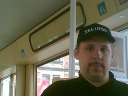 Ein Mann mit "Security"-Kappe steht in einem öffentlichen Transportmittel.