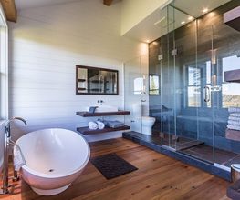 Modernes Badezimmer mit freistehender Badewanne, großer Dusche und Holzfußboden.