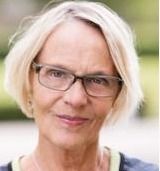 Jeg ved ikke, hvem personen er. En kvinde med kort lyst hår og briller kigger mod kameraet.