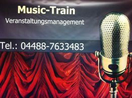 Ein Mikrofon vor rotem Vorhang, darüber steht "Music-Train Veranstaltungsmanagement".