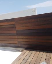 Panel de madera en terraza con suelo de tablones, cielo parcialmente nublado.