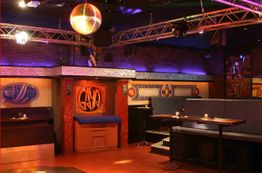 Eine Discothek mit Sofas, Tischen, bunten Lichtern und einer Diskokugel an der Decke.