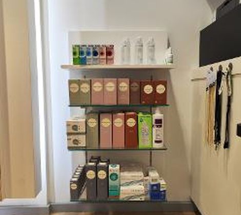 Plank met diverse schoonheidsproducten in een winkel, kleurrijke dozen en flessen op de vloer.