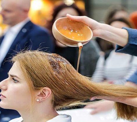 Donna riceve trattamento per capelli con liquido versato da una ciotola.