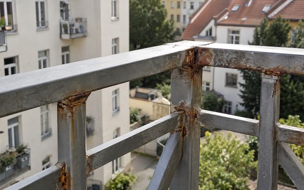 Rostendes Balkongeländer aus Metall mit deutlich sichtbarer Korrosion an den Schweißnähten.