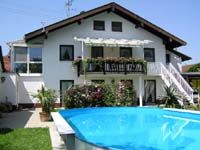 Zweistöckiges Haus mit Garten und einem runden blauen Pool im Vordergrund.