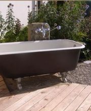 Drei Badezimmer: WC mit Urinal, freistehende Wanne im Freien, Doppelwaschbecken mit roter Wand.