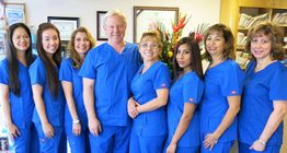 A group of medical professionals in blue scrubs standing together and smiling in an office.