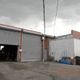Industrial building with two large garage doors, surrounded by an overcast sky.