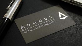 Schwarze Visitenkarte der AdMody Rechtsanwälte AG, neben einem silber-schwarzen Stift.