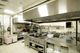 Commercial kitchen with stainless steel equipment and cooking appliances.