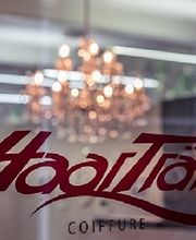 Friseursalon-Schriftzug „HaarTräff“ auf Fenster, im Hintergrund ein Kronleuchter.