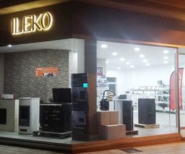 Tienda ILEKO iluminada, con electrodomésticos en exhibición y grandes ventanas de vidrio.