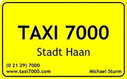 Gelbes Schild mit der Aufschrift "TAXI 7000, Stadt Haan" und Kontaktinfos unten.
