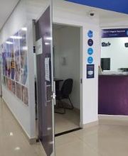 Corredor de clínica com porta aberta e balcão de recepção à direita. Paredes com pôsteres coloridos.