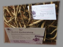 Visitenkarten der "Mobilen Kurberatung" auf Holzgeflecht mit lila Verzierungen.