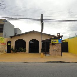 Fachada de uma loja com faixas amarelas, paredes de tijolo, e cobertura preta.