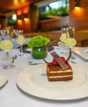 Postre elegante en plato blanco con bebidas en un restaurante iluminado y moderno.