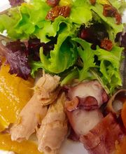 Ensalada gourmet con lechuga, puré, pescado y mariscos en un plato blanco.