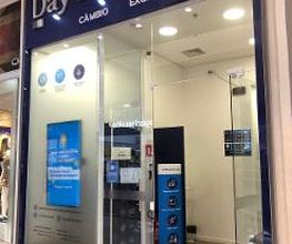 Fachada de uma casa de câmbio chamada DayCâmbio, com vitrines de vidro e sinalização externa.