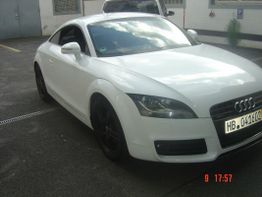 Ein weißer Audi TT steht auf einem Parkplatz, leicht von der Vorderseite fotografiert.