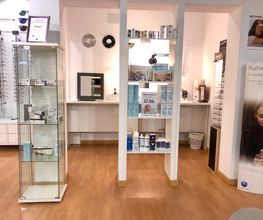 Óptica con estanterías y muestras de gafas, productos de cuidado ocular y carteles promocionales.