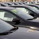 Row of black cars lined up for sale in a dealership lot.