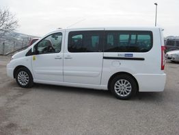 Furgone bianco parcheggiato su una strada asfaltata con paesaggio collinare sullo sfondo.