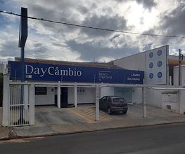 Fachada de uma agência de câmbio com um carro preto estacionado em frente.