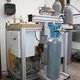 Maschine zur Gasabfüllung, mit grauen Gasflaschen und Steuerungen in einem industriellen Raum.